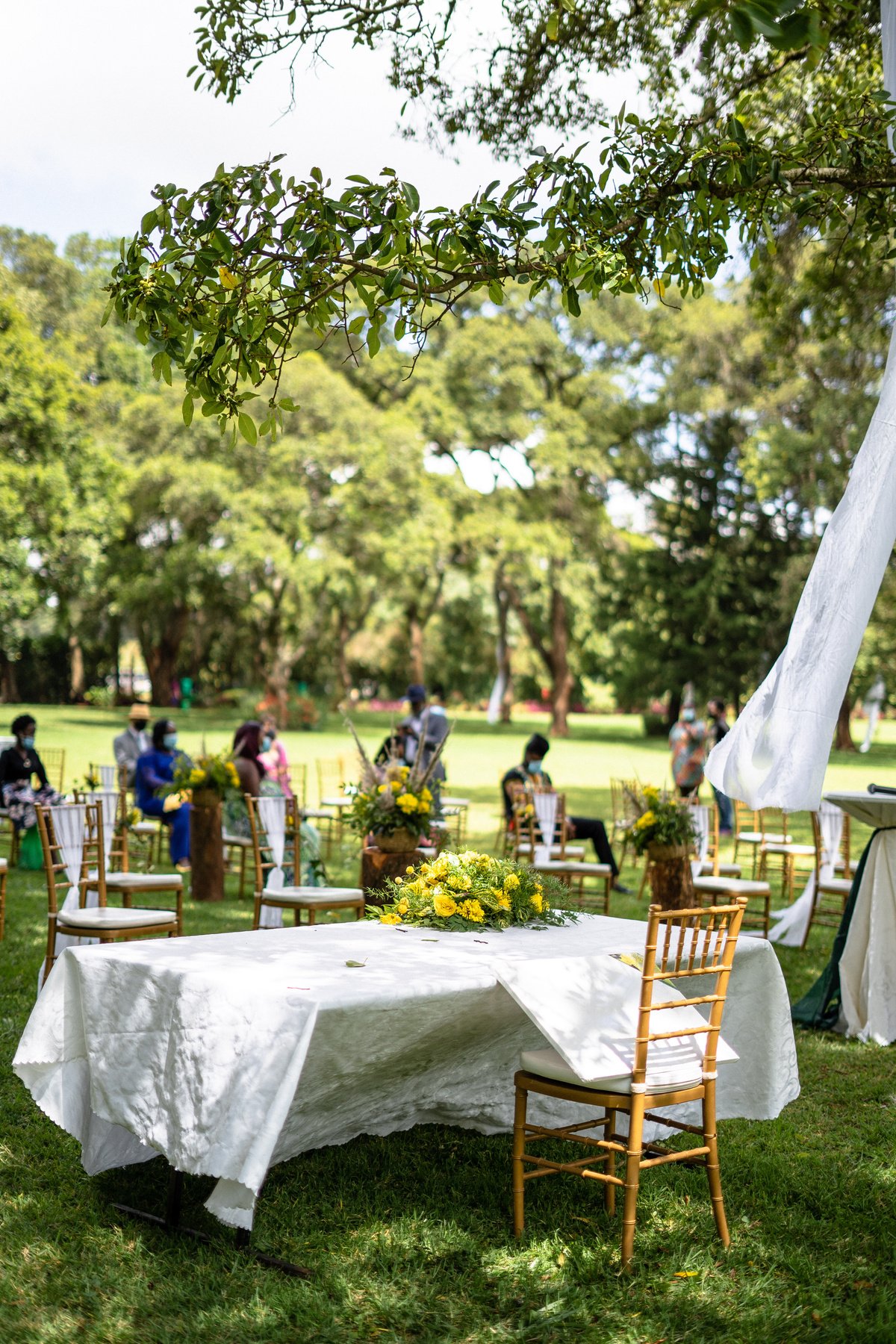 Vertical shot of an outdoor wedding venue with people sitting in masks